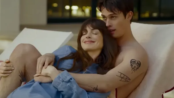 Anne Hathaway and Nicholas Galitzine snuggling on a couch in "The Idea of You"